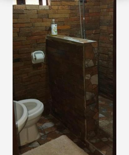 a bathroom with a toilet and a brick wall at Queen Room self contained in Lusaka