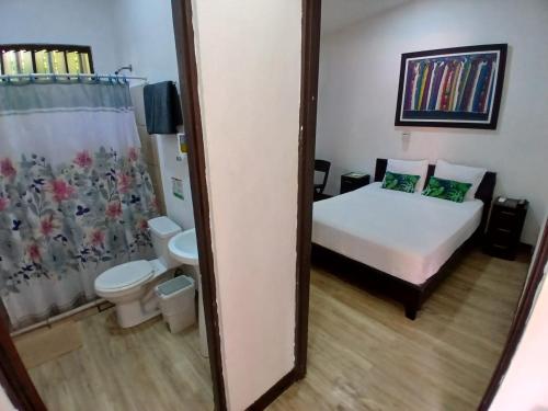 a bedroom with a bed and a toilet and a mirror at Hotel Jaco Lodge in Jacó