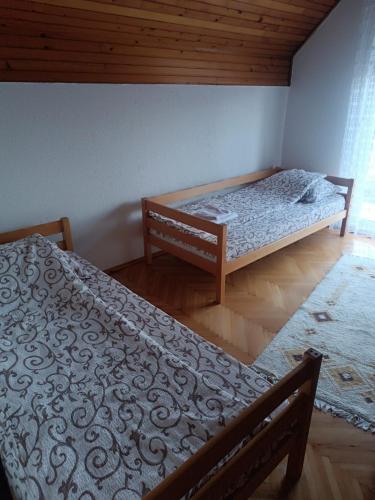 a bedroom with two beds and a wooden floor at Vikendica Miki 2 in Bratunac