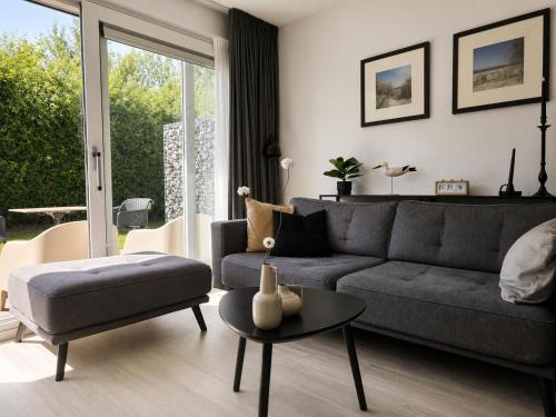 a living room with a gray couch and a table at Prins Prachtig Amelander Kaap 97 in Hollum