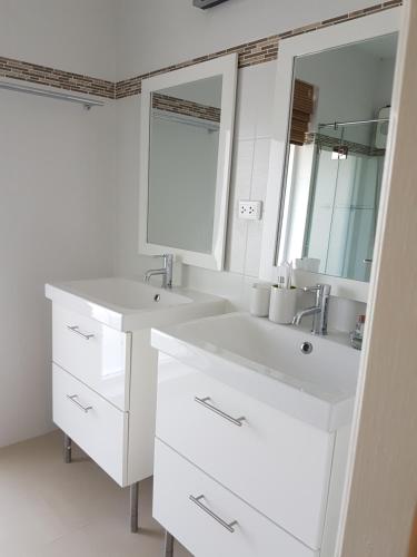 a white bathroom with two sinks and a mirror at The Hillside Pranburi Resort in Pran Buri