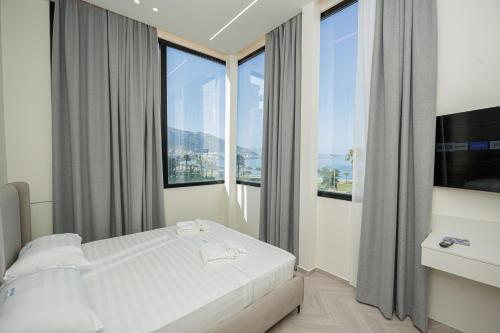 a bedroom with a bed and large windows at Laid Hotel in Vlorë