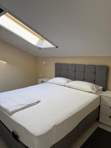 a bedroom with a large white bed with a skylight at Vivko apartmani 2 in Ostrovo