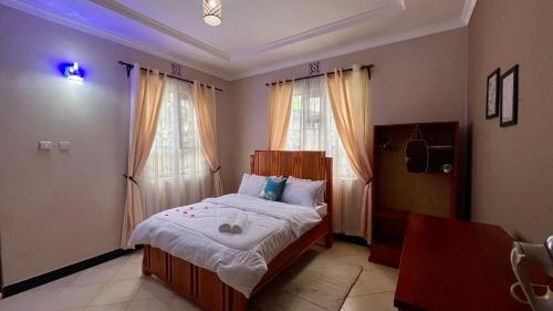 a bedroom with a bed and two windows at Jubilant Experience Homes Arusha in Arusha