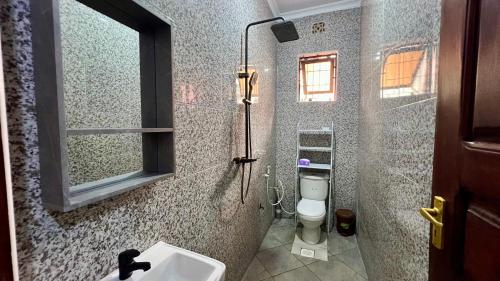 a bathroom with a toilet and a sink and a window at Jubilant Experience Homes Arusha in Arusha