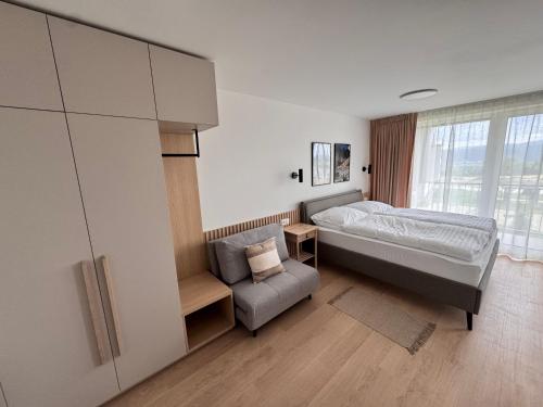a bedroom with a bed and a chair and a window at Apartment Tatry Gerlachov, Vysoke Tatry in Svätý Jur