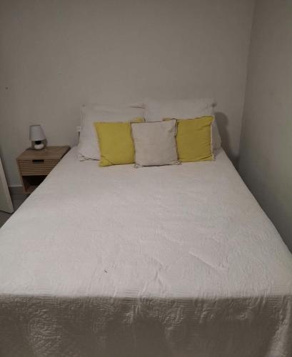 a white bed with two yellow pillows on it at Chez Ava in Salazie