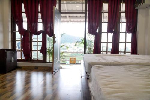 a bedroom with two beds and a large window at Arupa Homestay in Ooty