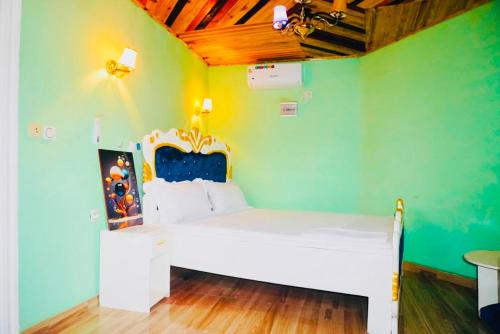 a bedroom with a white bed in a green wall at point de distraction in Foumban