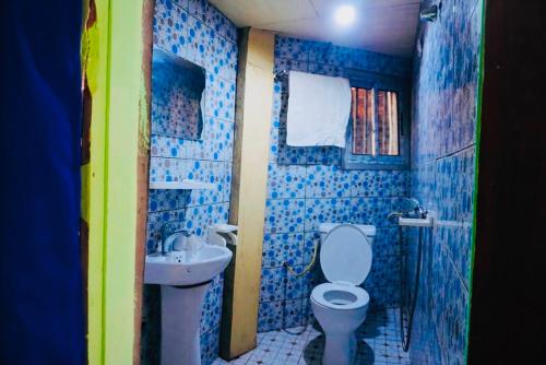 a blue tiled bathroom with a toilet and a sink at point de distraction in Foumban