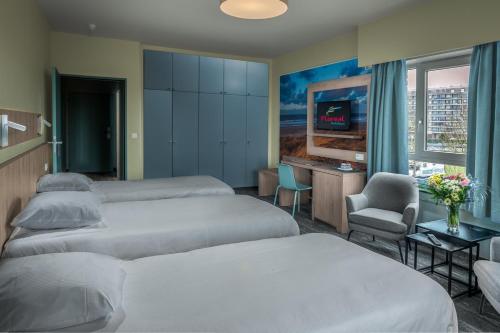 a hotel room with three beds and a desk and a tv at Floreal Blankenberge in Blankenberge