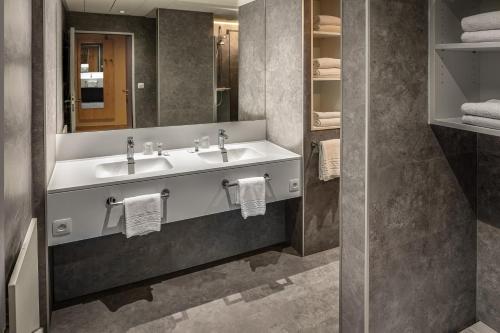 a bathroom with two sinks and a mirror and towels at Floreal Blankenberge in Blankenberge
