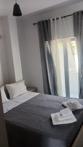 a bedroom with a bed and a window with towels on it at Vana's Apartments in Sarandë