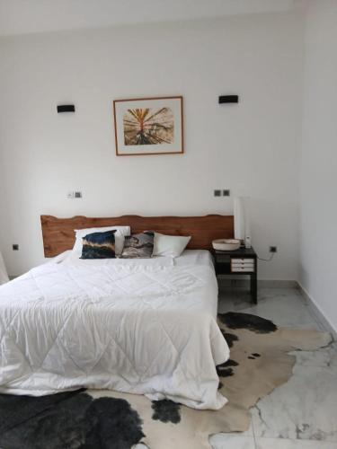 a bedroom with a large white bed and a table at Villa Blanche in Cotonou