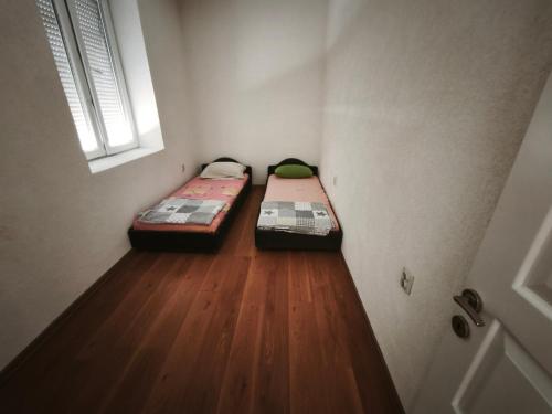 two beds in a room with a wooden floor at Spacious City Center Apartment for 6 - Steps from Hilton & Republic Square in Podgorica