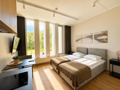 a bedroom with a bed and a tv and windows at Emajõe Apartments in Tartu