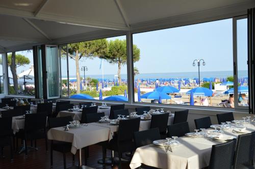 ein Restaurant mit Tischen und Stühlen und Blick auf den Strand in der Unterkunft Hotel La Bussola in Lido di Jesolo
