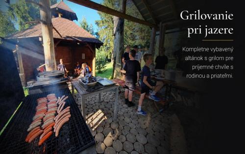 a group of people standing around a grill with hot dogs at Penzion Kormoran in Námestovo