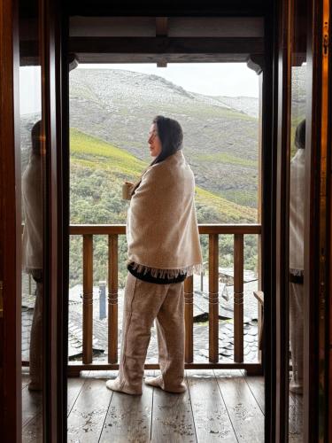 a woman looking out the window of a house at Lar da cima in Folgoso