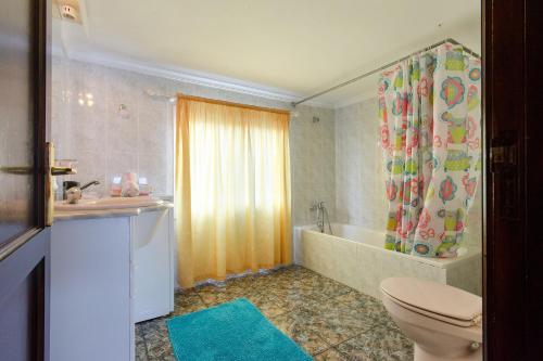 a bathroom with a toilet and a tub and a shower curtain at Caleta Blue House - Macaronesiahome in Caleta de Caballo