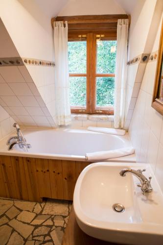 a bathroom with a tub and a sink and a window at Siódmy Las in Zawada
