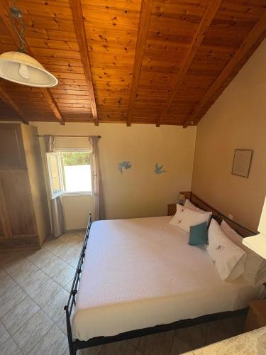 a large bed in a room with a wooden ceiling at AMYGDALIA in Vlachopoulátika