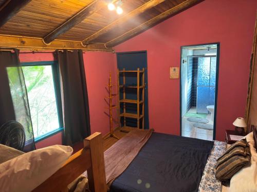 a bedroom with red walls and a bed and a ladder at Pousada Tiê-Sangue in Iporanga