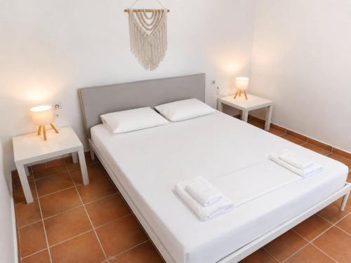 a bedroom with a white bed and two tables at Natasa private garden apartment in Polychrono