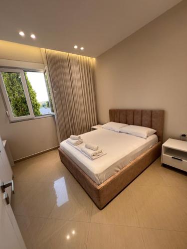 a bedroom with a bed with white sheets and a window at Aron apartments in Tirana