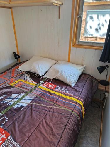 a bed in a small room with a window at Camping du lac chalet P62 in Foix