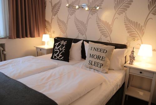 1 dormitorio con 1 cama con sábanas y almohadas blancas en Hotel Krone Aachen | City-Eurogress en Aachen