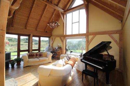 a living room with couches and a piano at Beautiful Stone Riverside Retreat Galway in Galway