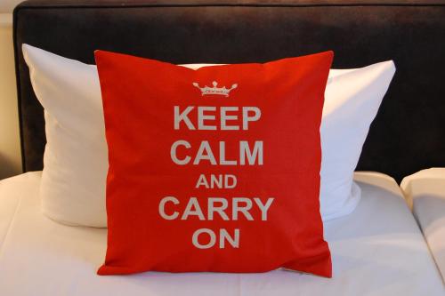 una almohada roja con las palabras mantener la calma y continuar en Hotel Krone Aachen | City-Eurogress, en Aachen