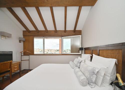 a bedroom with a large white bed with white pillows at Hotel Principe Real in Lisbon