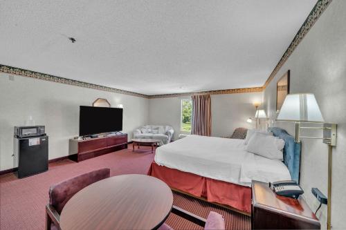 a hotel room with a bed and a flat screen tv at Gray Inn & Suites in Gray