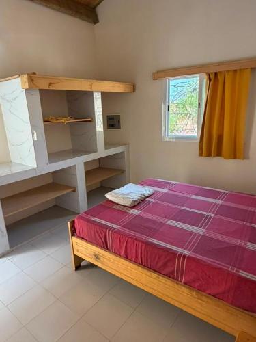 a bedroom with a bed and a window and a shelf at Le Clos Rivière in Ndangane