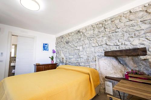 a bedroom with a stone wall and a yellow bed at Casa Isca in Trentinara