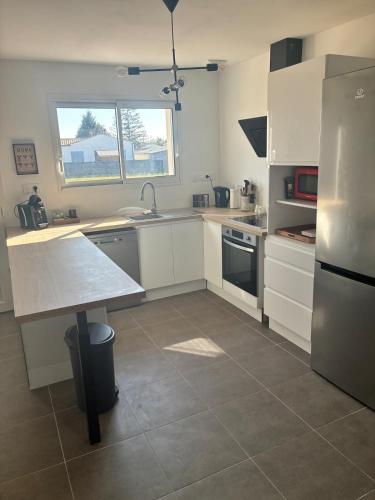 a kitchen with white cabinets and a stainless steel refrigerator at Maison chaleureuse in Migron