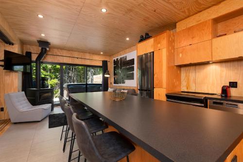 a kitchen with a large black counter top and chairs at Les Refuges du Massif de Charlevoix in Petite-Rivière-Saint-François