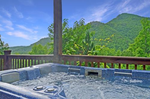a hot tub on a deck with mountains in the background at Free Railroad Tix - secluded - Fire Pit and Outdoor Bed Swing in Talc Mountain