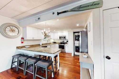 a kitchen with white cabinets and a island with bar stools at White Marlin 202A in Ocean City