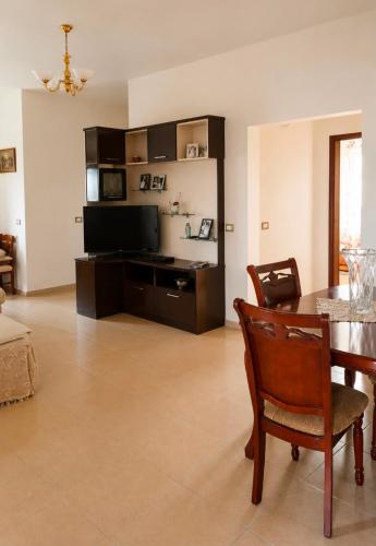 ein Wohnzimmer mit einem Tisch und einem Fernseher in der Unterkunft Hamallaj in Hamallë