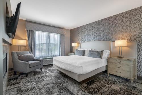 a bedroom with a bed and a chair and a window at Best Western PLUS Franklin Square Inn in Troy