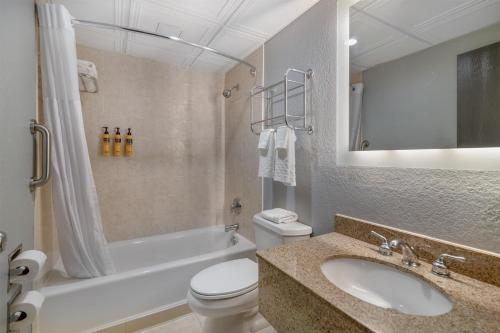 a bathroom with a sink and a toilet and a tub at Best Western PLUS Franklin Square Inn in Troy