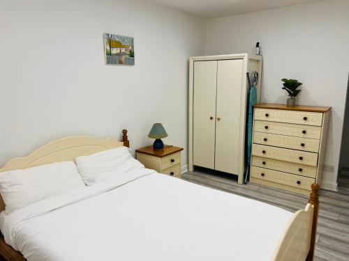 a bedroom with a white bed and a dresser at Ideal Guest House in Carrick-on-Suir