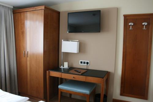 a bedroom with a television and a desk at Dürer-Hotel in Nuremberg