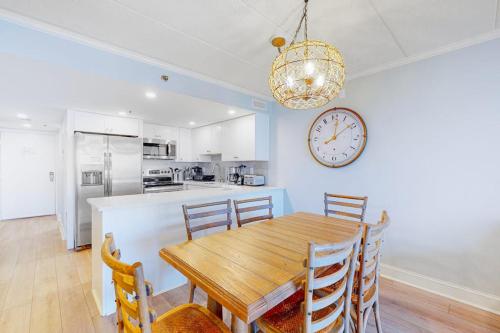 a dining room with a table and a clock on the wall at Summer Beach 602 in Ocean City