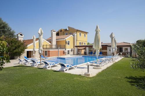 a swimming pool with white chairs and umbrellas at Villa Suzanne in Banjole