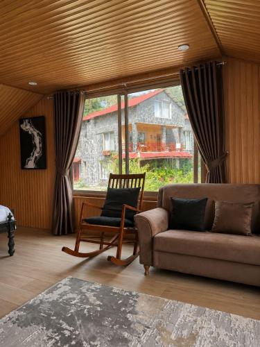 a living room with a couch and a chair and a window at The Cozy Cottage, Dunga Gali in Dunga Gali