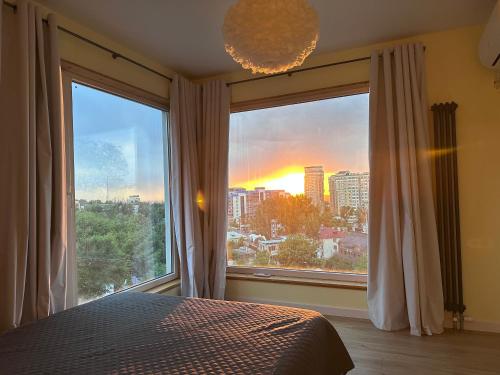 a bedroom with a large window with a view of the city at Altura House in Almaty